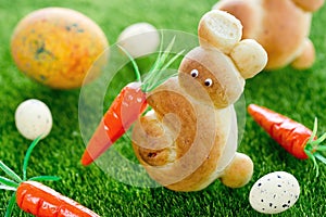 Easter bunny buns with carron and easter eggs on green grass background