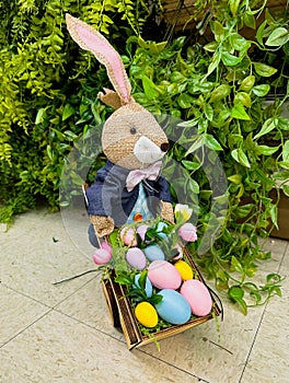 Easter bunny with a cart on a green background with Easter colored eggs