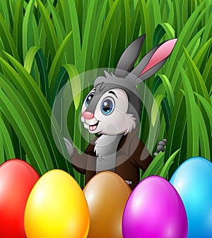 Easter bunny and colorful eggs in the grass bushes