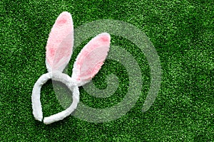 Easter bunny concept. Toy rabbit`s ears for head on green grass background top-down copy space