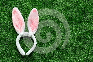 Easter bunny concept. Toy rabbit`s ears for head on green grass background top-down copy space