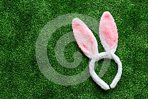 Easter bunny concept. Toy rabbit`s ears for head on green grass background top-down copy space