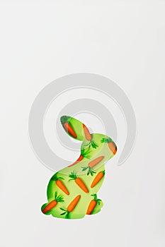 Easter bunny greeting card. Cut out bunny shape with small decorative carrots in the background