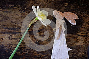 Easter bunny made from straw and narcissus plant in flower pot on wooden