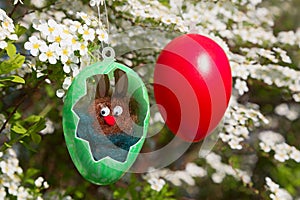 Easter bunny in a plastic egg with cut out. blooming spiraea bush