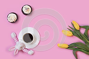 Easter bunny rabbit, cakes, white coffee cup and spring tulip flowers on pink background. Flat lay, copy space for text. Happy