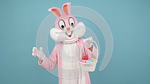 Easter bunny or rabbit or hare cute kid boy or girl holds basket of colored eggs, dancing having fun, celebrate Happy