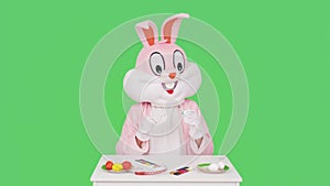 Easter Bunny or rabbit or hare is painting eggs, prepares celebrates Easter isolated on chromakey or green background