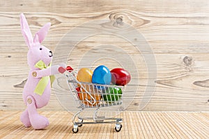 Easter bunny with a shopping cart full of colorful easter eggs