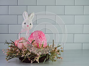 Easter bunny on a stick with a giant pink Easter egg and 3 smaller pink Easter eggs sitting in a spring pink and green wreath on a