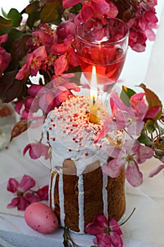 Easter cake with a burning candle and red wine on the holiday table