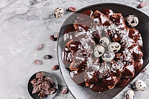 Easter cake with chocolate, coconut, spring flowers, quail eggs on a stone background. Happy Easter celebration. Top view,flat lay