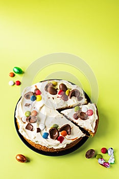 Easter cake with chocolate eggs, candies and cream cheese frosting. Top view and copy space