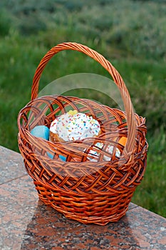 Easter cake and colorful Easter eggs in wicker basket