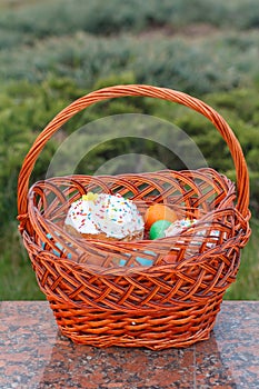 Easter cake and colorful Easter eggs in wicker basket