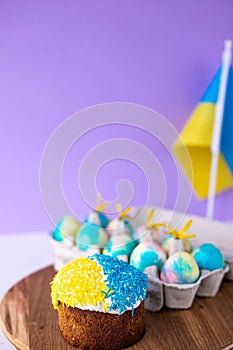 Easter cake decorated in colors of Ukrainian flag and eggs painted in yellow blue, laid out around it. easter concept