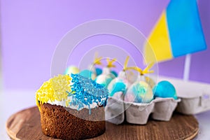 Easter cake decorated in colors of Ukrainian flag and eggs painted in yellow blue, laid out around it. easter concept