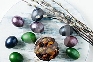 Easter cake with dried fruits and chocolate on a pastel background with colored eggs and willow twigs. top view