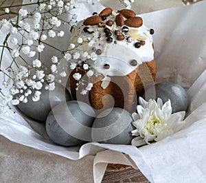 Easter cake and gray painted eggs in a basket decorated with white flowers.