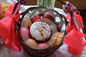 Easter cake with painted eggs lies in a dark brown basket.