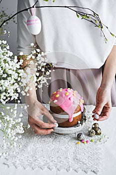 Easter cake with pink decor, white flowers and woman hands