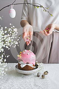 Easter cake with pink decor, white flowers and woman hands