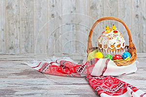 Happy Easter! Easter Cake - Russian and Ukrainian traditional kulich and colorful eggs in a wicker basket on an embroidered towel.