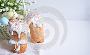 Easter cake with spring flowers and colorful eggs in a basket on a white table. Selective focus. Copy the place for the