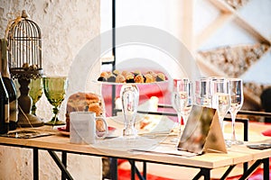 Easter cake, sweets on a glass stand, two bottles of champagne, glasses and a mug on the table