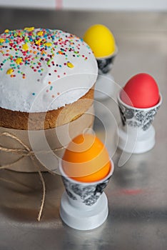Easter cake with a white top, decorated with multi-colored sprinkles and colored Easter eggs on kitchen table