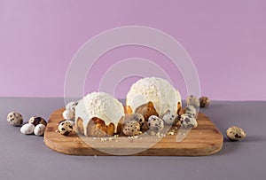 easter cakes covered with white glaze quail eggs on a wooden cutting board side view easter still life