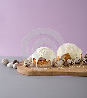 easter cakes covered with white glaze quail eggs on a wooden cutting board side view easter still life