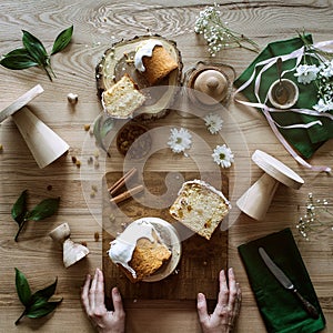 Easter cakes and flowers on a wooden table and hands