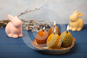 Easter candle eggs and willow branches on textural background.