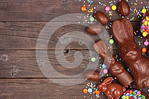 Easter candy, chocolate bunny and egg side border against a dark wood background