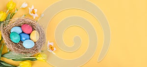 Easter card background baner, Easter eggs with a bouquet of yellow tulips and daffodils on a yellow background, with copy space