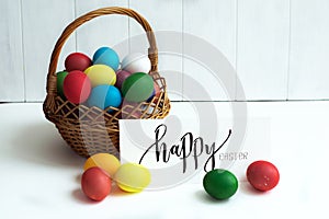 Easter card with colorful Easter eggs in a basket and calligraphic inscription `Happy Easter`