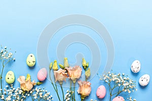 Easter card in pastel colors. Decorative eggs, white Gypsophila, peach Eustoma flowers on blue.
