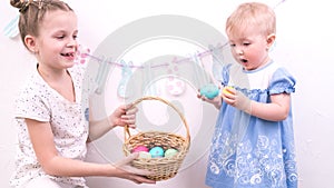 Easter celebration: The girl treats her younger sister with painted Easter eggs from a wicker basket.