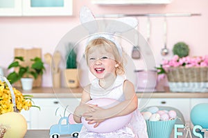 Easter child portrait, funny emotions. Kid with bunny ears in the kitchen in the house laughs happily. The baby holds a