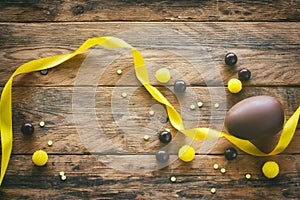 Easter chocolate egg, candy dragees, yellow silk ribbon