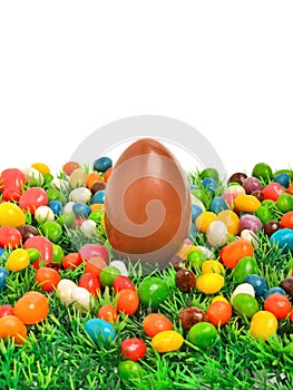 Easter chocolate egg and caramels on the green grass