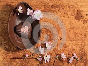 Easter chocolate egg with a surprise of a decorated heart ,sprinkled with cocoa powder and accompanied with almond blossom.