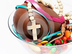 Easter chocolate egg , sweets and cross in a glass
