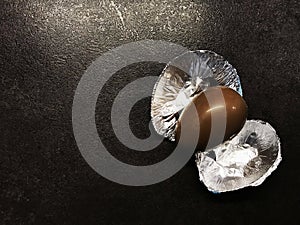 Easter chocolate kinder egg with a foil on a black table