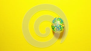 Easter colored egg is pumped into the yellow background.Flat lay stop motion animation