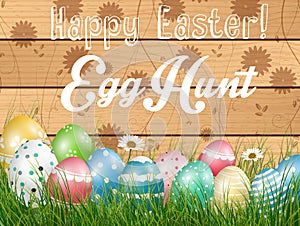 Easter colored eggs on grass with flower on wooden background