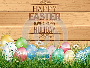 Easter colored eggs on grass with flower on wooden background