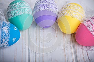 Easter colored eggs with lace ribbon on white wooden background photo