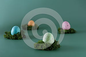 Easter colored eggs laying on the moss pillow on the green background. Happy Easter holiday. Muted colors. Selective